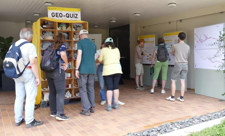 Mehrere Personen stehen vor einer Art Holzregal mit vielen Fächern