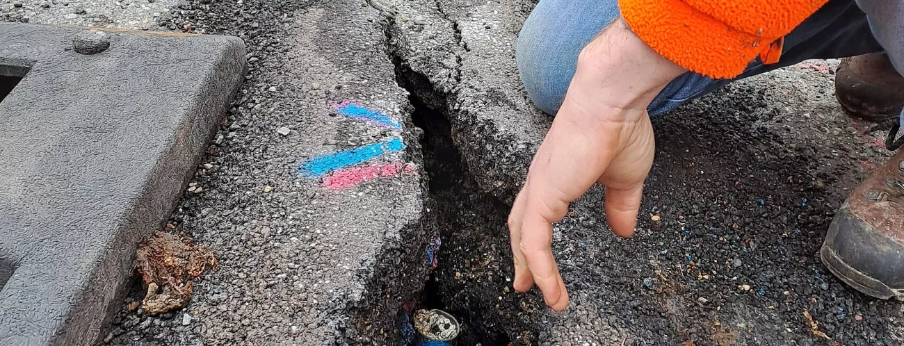 Ausschnitt aus einer Fahrbahndecke mit Längsspalt in Dreiecksform und farbigen Markierungen